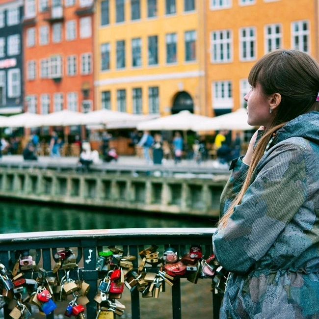 Une femme contemplant un pont orné de cadenas, symbole d'amour et d'engagement, sous un ciel dégagé.