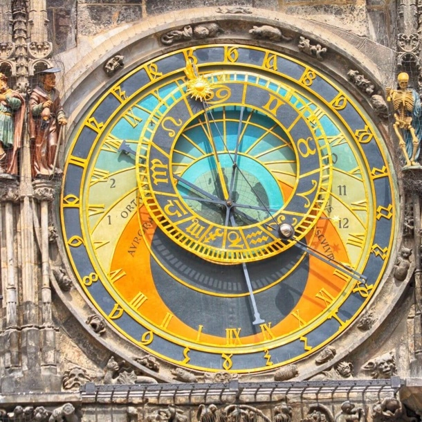 The image shows an ornate astronomical clock with Roman numerals, zodiac signs, and various colored areas. The intricate design and historical significance make it a fascinating piece of architecture.