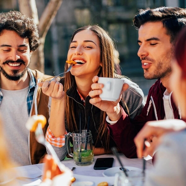 Un groupe d'amis partage un repas tout en dégustant des cafés dans une ambiance conviviale et chaleureuse.