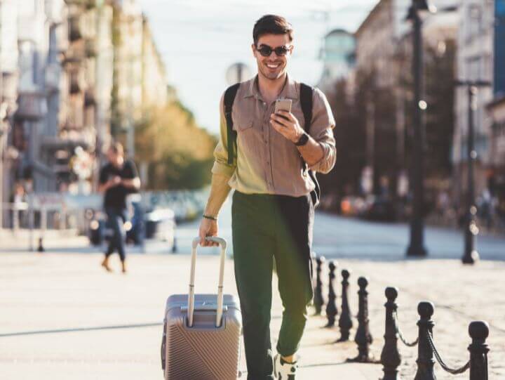 man smiling and looking at his phone while walking