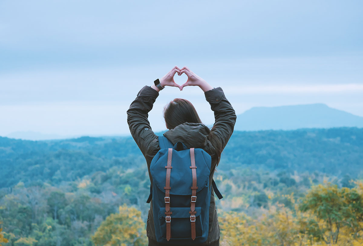 Image of a traveller making the love heart symbol with her hands