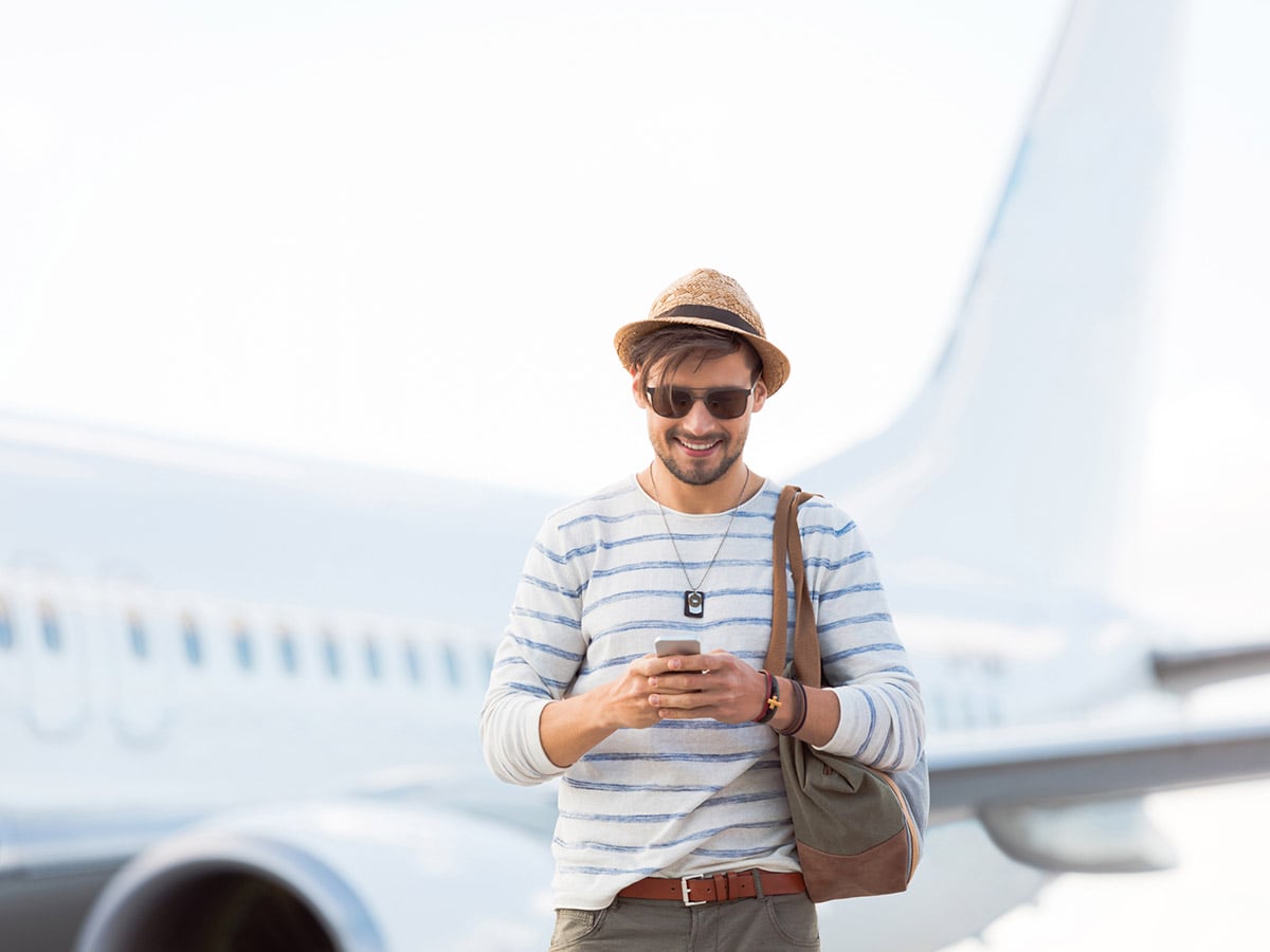 Man with his phone in front of airplane